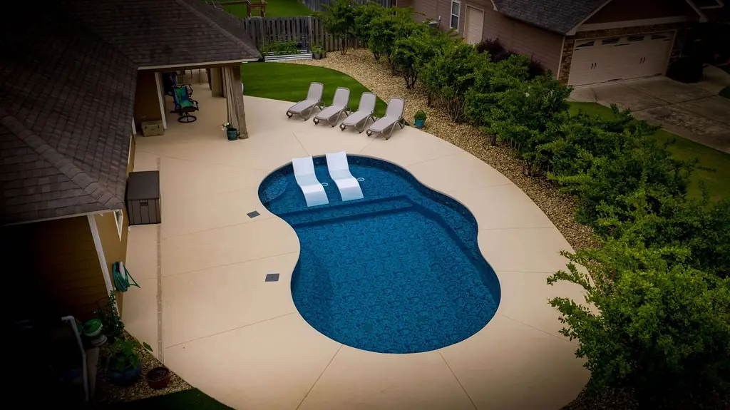 Kidney-shaped pool with loungers on the deck beside it