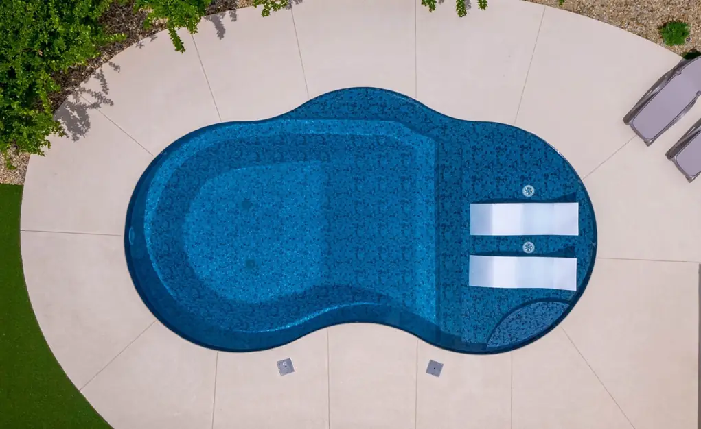Overhead view of a kidney-shaped pool showing its patterned liner through clear water