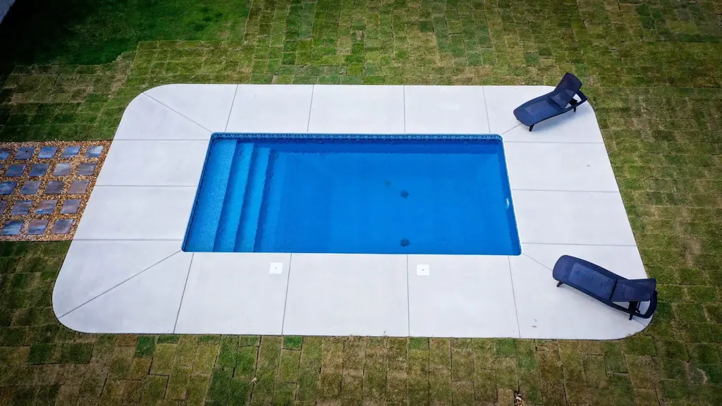 Newly finished rectangular pool on fresh sod squares with two loungers on its white deck